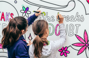 Two young girl coloring in graphics wall together